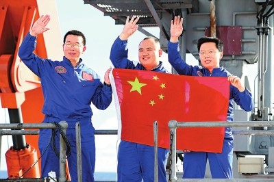 △2012年6月24日,“蛟龙”号三位试航员崔维成、叶聪、杨波(左至右)手举国旗向众人致意。