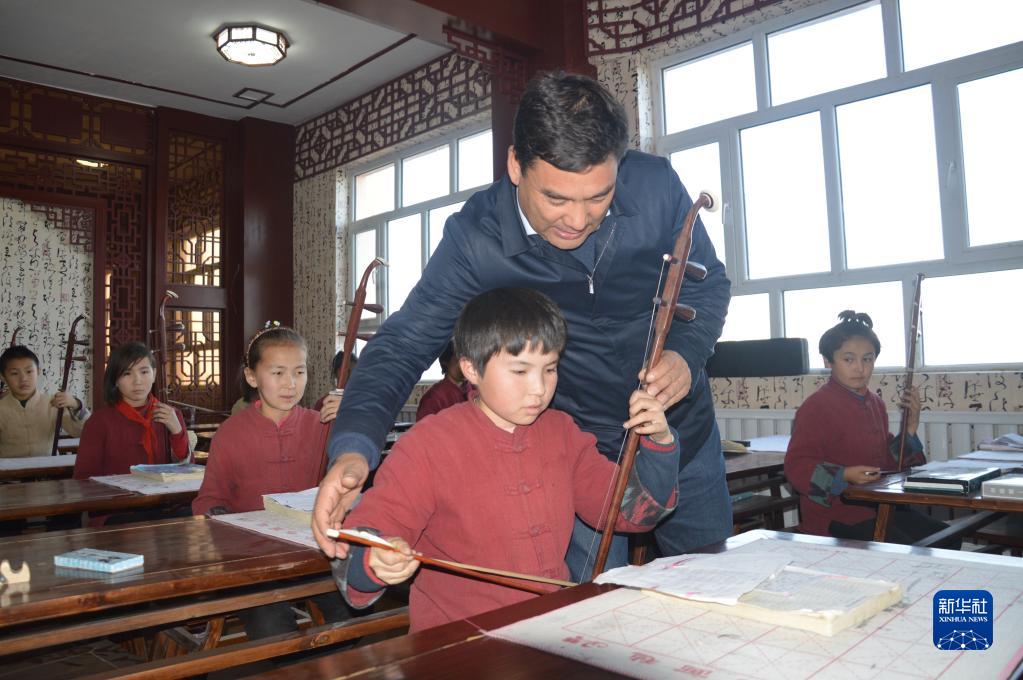 在新疆乌什县依麻木镇国家通用语言小学，库尔班·尼亚孜辅导学生拉二胡（资料照片，2018年11月摄）。新华社发